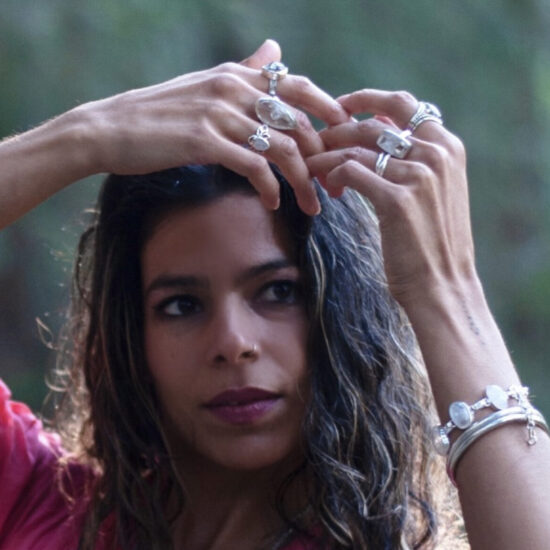 Woman in pink dress featuring Esprit Creations sterling silver glowing moon-stone rings and bracelet. Available wholesale from conscious artisan jewelry importers and designers. 